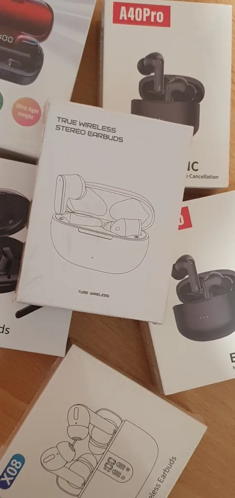 Mehrere Verpackungen kabelloser Bluetooth-Ohrhörer nebeneinander auf einem Holztisch