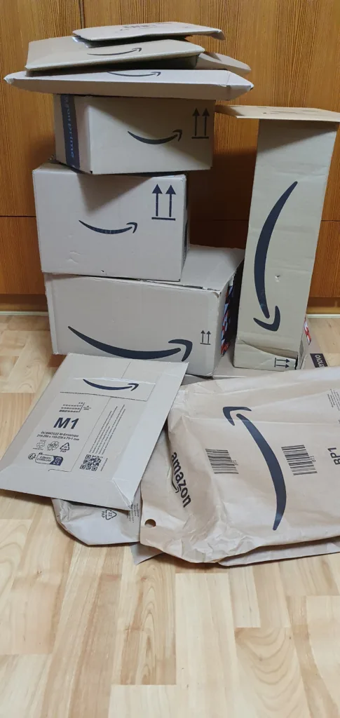 Turm aus Amazon-Kartons neben einem hohen schmalen Paket und mehreren Versandtaschen