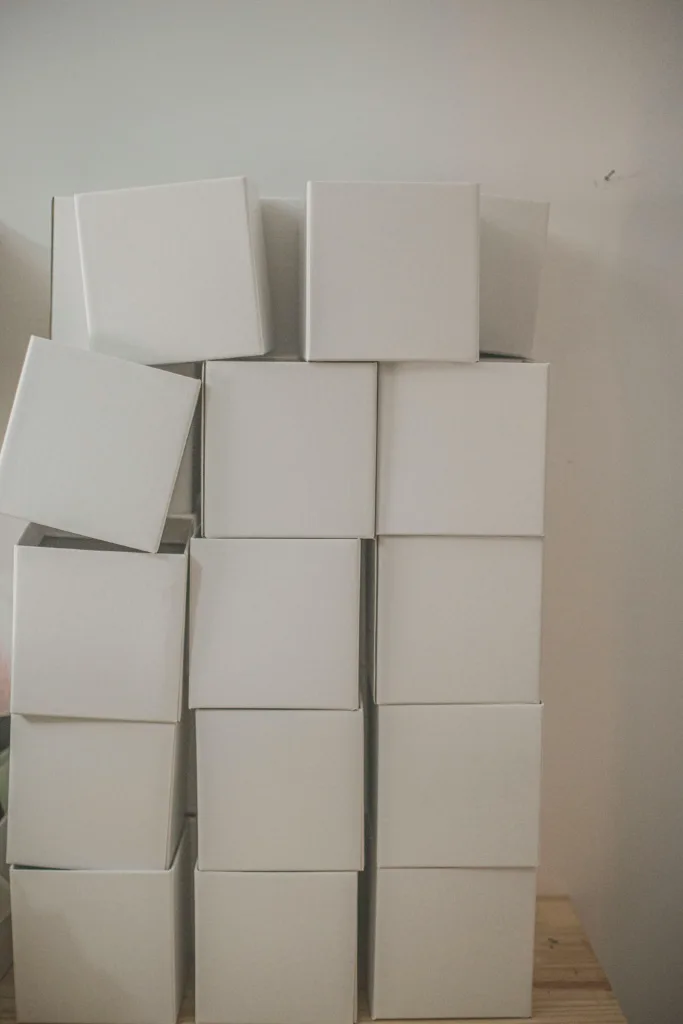 Turm aus gleichförmigen weißen Produktkartons an einer Zimmerwand